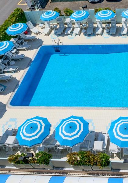 Piscina all'aperto con ombrelloni blu e lettini.