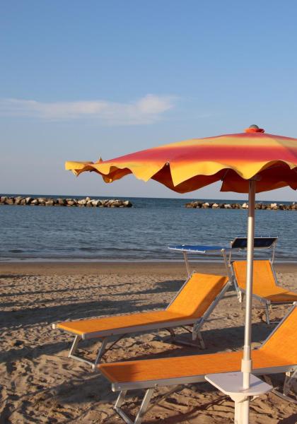 Beach with orange umbrellas and loungers, calm sea in the background.