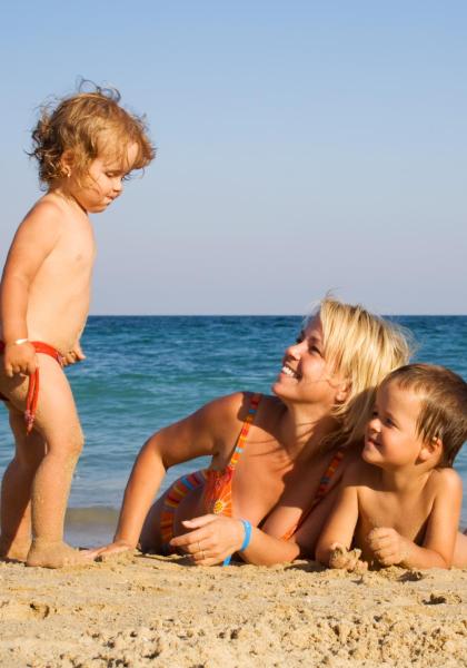 Famiglia felice gioca sulla spiaggia al tramonto.