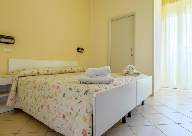 Camera luminosa con letto floreale e asciugamani bianchi, atmosfera accogliente.