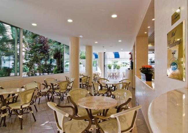 Sala con tavoli e sedie, ambiente luminoso e accogliente.