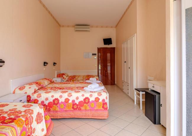 Camera d'albergo con letti colorati e arredi semplici.