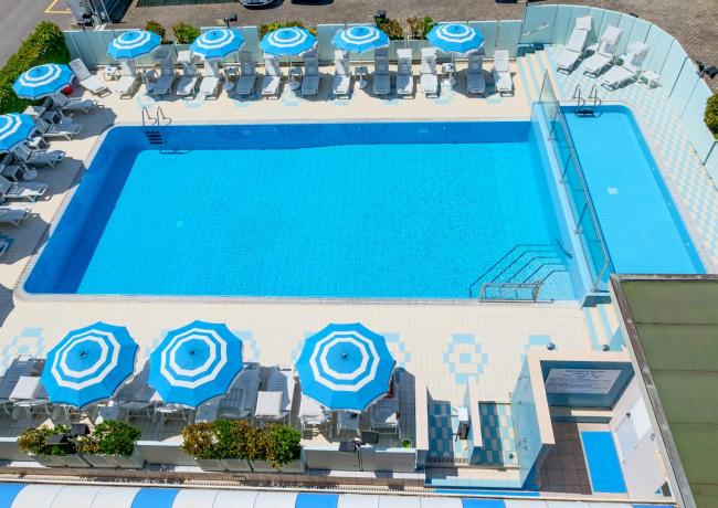 Piscina all'aperto con ombrelloni blu e lettini.