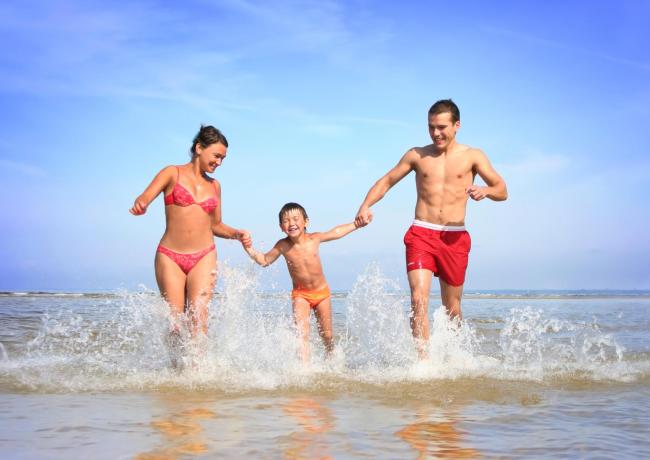 Glückliche Familie rennt im Meerwasser.