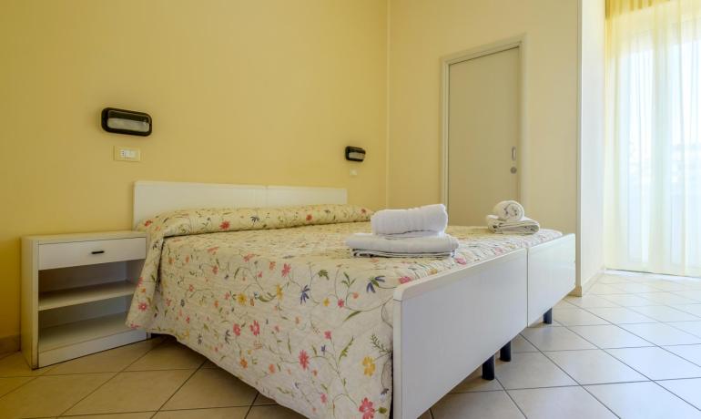 Camera luminosa con letto floreale e asciugamani bianchi, atmosfera accogliente.