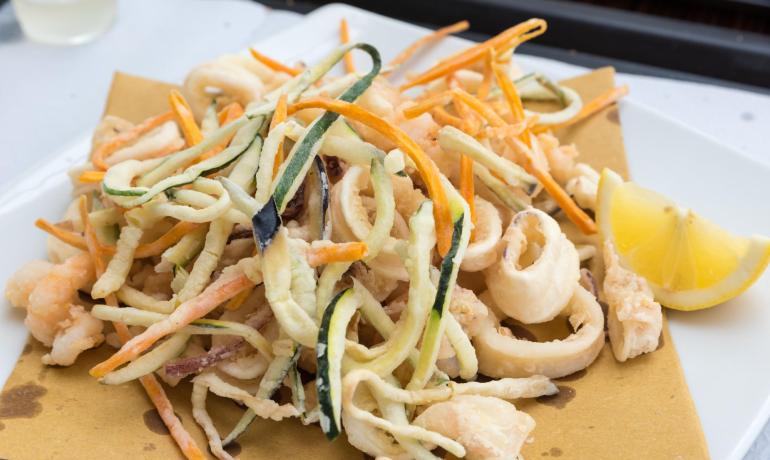 Frittura croccante di calamari e verdure con limone, aroma di mare.