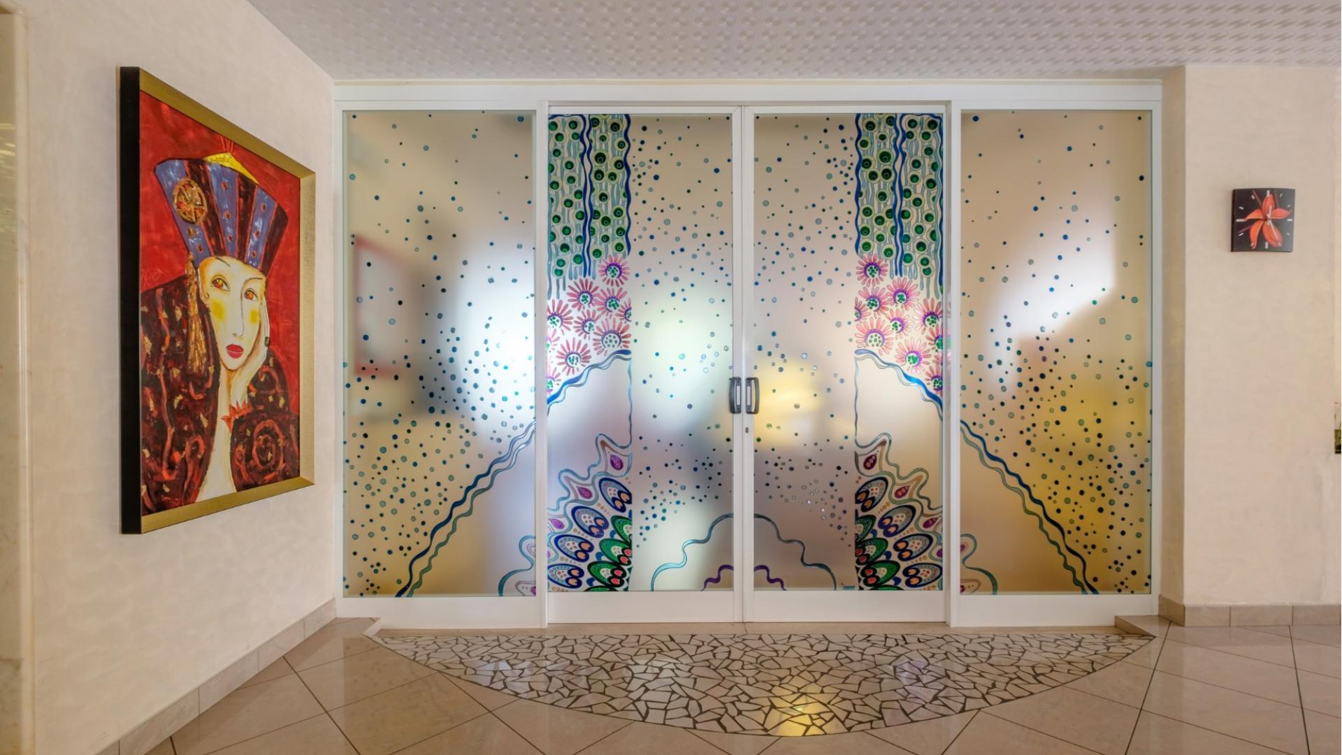 Porta decorata con motivi colorati, affiancata da un quadro vibrante e astratto.