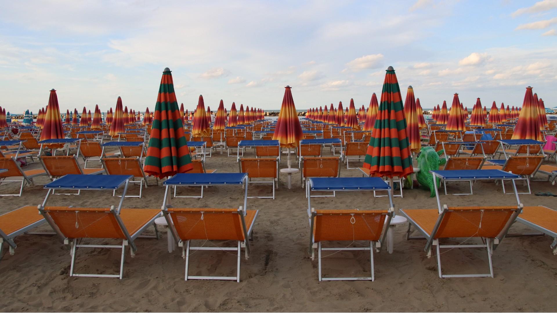 Spiaggia con ombrelloni colorati e lettini, atmosfera estiva e rilassante.