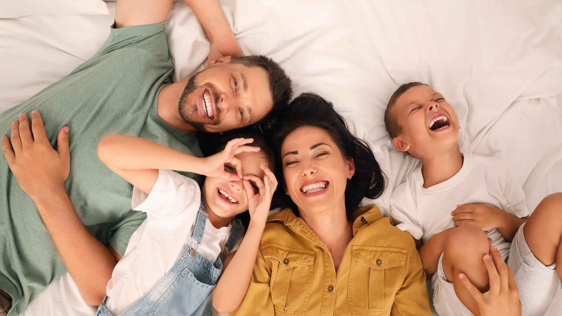 Famiglia felice e sorridente sdraiata insieme, trasmette gioia e amore.