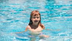 Bambino felice gioca in piscina, acqua scintillante e cielo sereno.