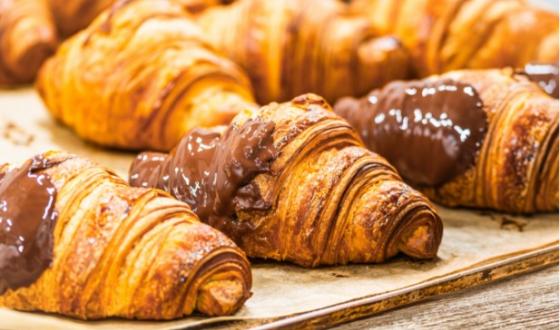 Croissant dorati, fragranti, con cioccolato fuso che avvolge, evocano dolcezza e piacere irresistibile.