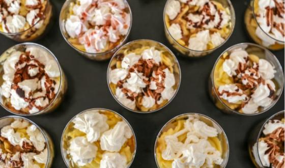 Bicchieri di dessert cremosi, decorati con panna montata e cioccolato, invitano al piacere.