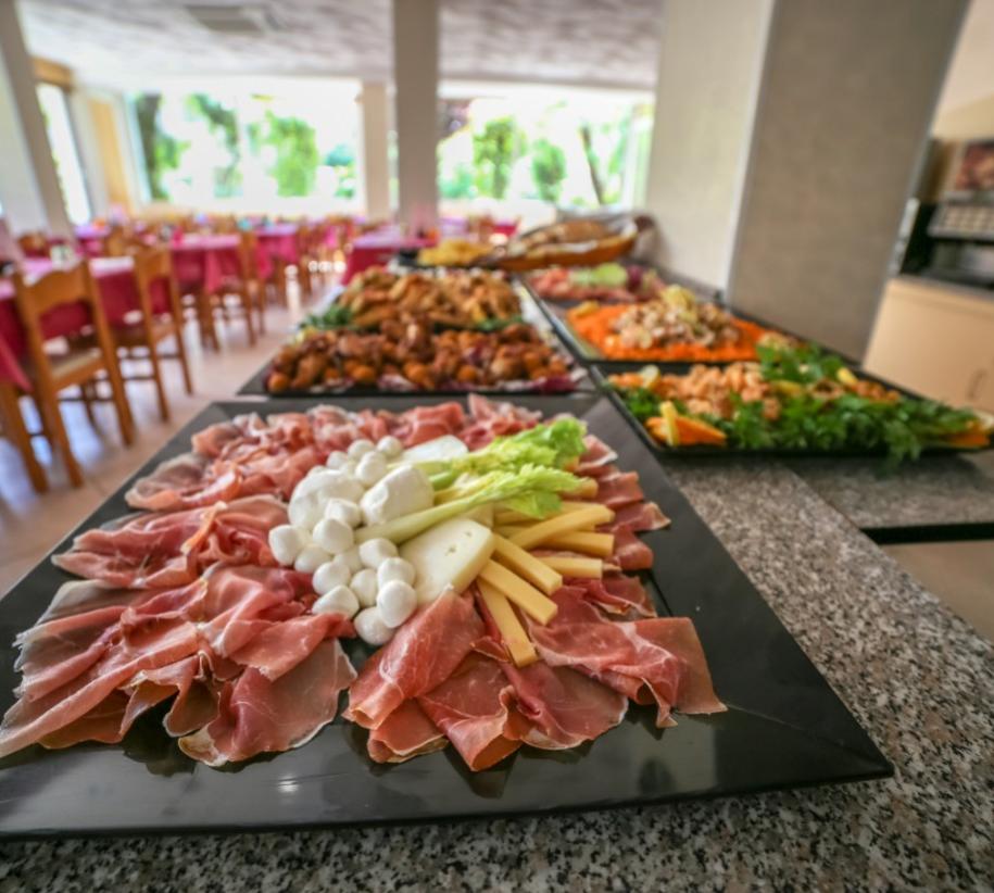 Un buffet colorato con affettati, formaggi e verdure, in un'accogliente sala da pranzo.