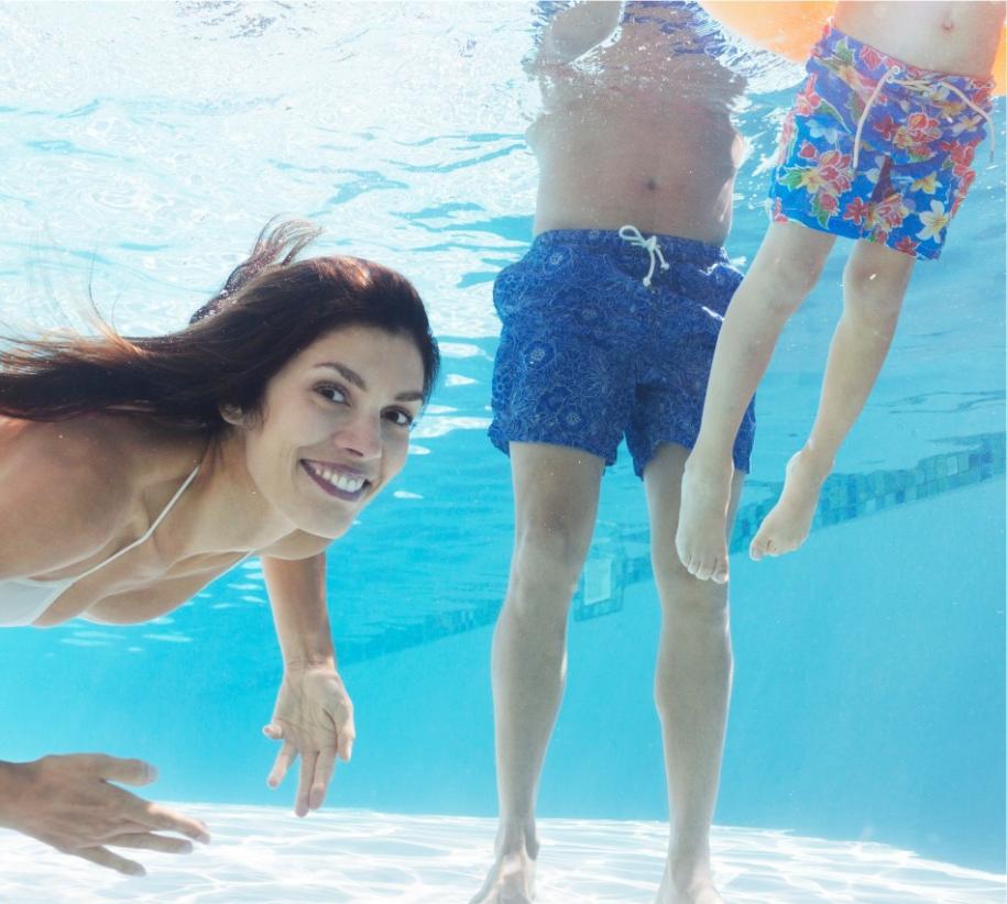 Sorrisi sott'acqua, gioia familiare, estate, costumi colorati, divertimento e spensieratezza in piscina.