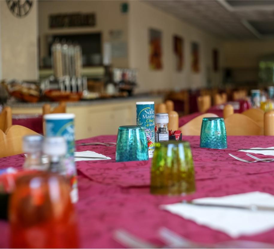 Tavola apparecchiata, bicchieri colorati, atmosfera accogliente, pronta per un pasto conviviale.