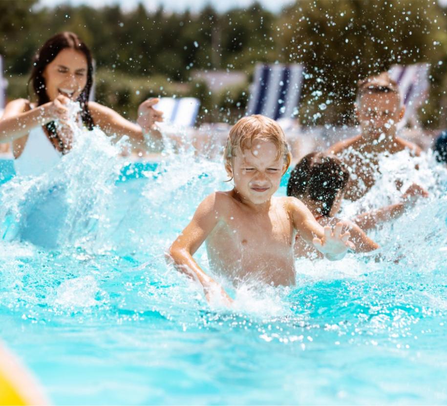 Bambini giocano felici in piscina, spruzzi d'acqua e risate sotto il sole estivo.